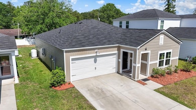 View of front of home featuring a shingled roof, an attached garage, concrete driveway, and a front yard