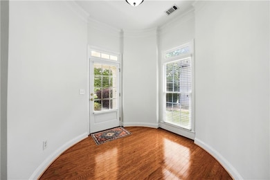 Entryway with wood finished floors, crown molding, baseboards, and a towering ceiling