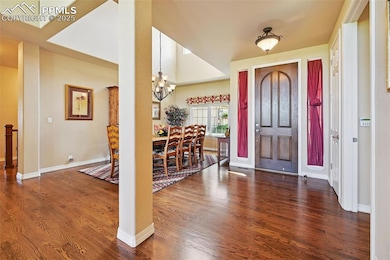 Entrance foyer with a chandelier, wood finished floors, and vaulted ceiling