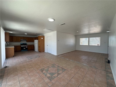 Unfurnished living room featuring a textured ceiling and light tile patterned flooring