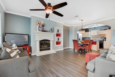 Living area with crown molding, ceiling fan, a gl