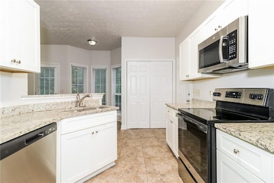 Kitchen featuring sink, a textured ceiling, white 