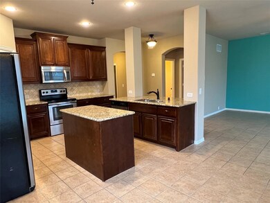 Kitchen featuring backsplash, stainless steel appliances, sink, light tile floors, and a center island with sink