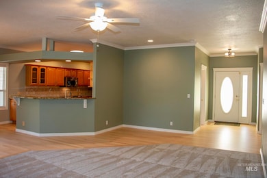 Foyer entrance with light wood finished floors, a textured ceiling, ornamental molding, ceiling fan, and recessed lighting