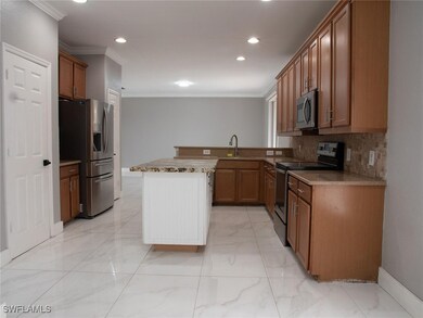 Kitchen featuring appliances with stainless steel finishes, ornamental molding, brown cabinetry, backsplash, and light marble finish floors