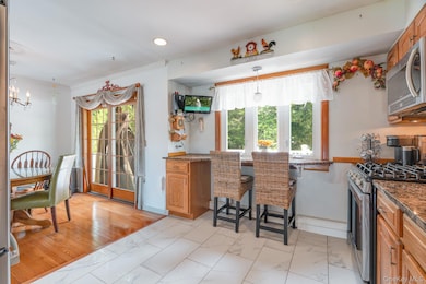 Kitchen with appliances with stainless steel finishes, dark stone countertops, brown cabinets, light marble finish floors, and recessed lighting