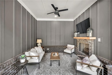 Outdoor Living room with a decorative wall, ceiling fan, a brick fireplace, and crown molding