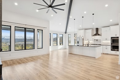 Kitchen featuring white cabinetry, open floor plan, a center island with sink, decorative backsplash, and recessed lighting