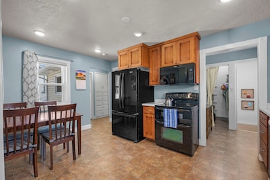 Kitchen with black appliances, brown cabinets, light countertops, a textured ceiling, and recessed lighting