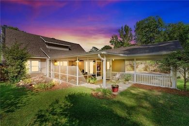 Back of property at dusk with a patio, a yard, a shingled roof, and a sunroom