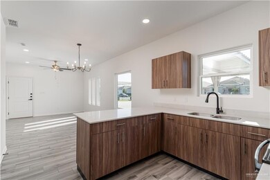 Kitchen with a peninsula, light wood-style flooring, a sink, visible vents, and light countertops