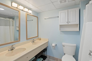 Bathroom featuring a drop ceiling, vanity, tile pa