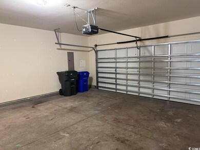 Garage featuring a garage door opener and electric panel