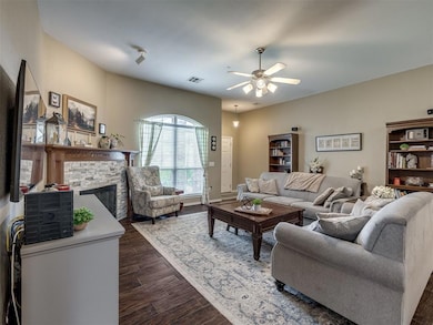 Living room with a ceiling fan, dark wood-style floors, and a fireplace