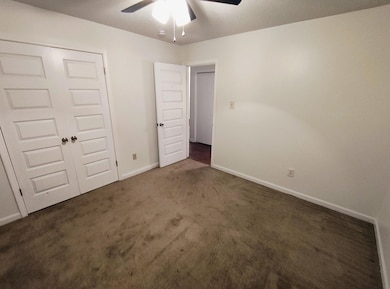 Unfurnished bedroom featuring carpet, baseboards, a closet, and a ceiling fan