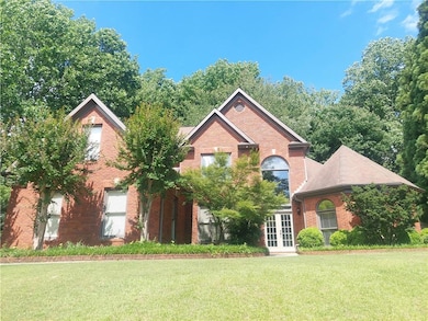 View of front facade featuring french doors, brick siding, and a front yard