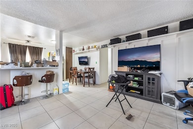 Living area with a textured ceiling and light tile patterned flooring