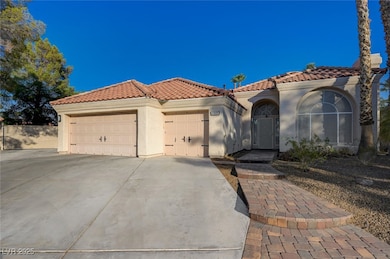 Mediterranean / spanish home with a tile roof, a garage, driveway, and stucco siding