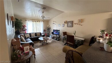 Tiled living room featuring ceiling fan and vaulted ceiling