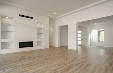 Unfurnished living room with a glass covered fireplace, built in features, light wood finished floors, and recessed lighting