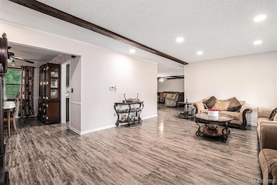 Living room with a ceiling fan, wood finished floors, beam ceiling, a textured ceiling, and recessed lighting