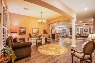 Living area featuring arched walkways, a chandelier, dark wood finished floors, ceiling fan, and recessed lighting
