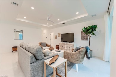 Living area with a raised ceiling, recessed lighting, a ceiling fan, and light tile patterned flooring