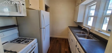 Kitchen featuring white appliances, white cabinets, and dark wood-type flooring