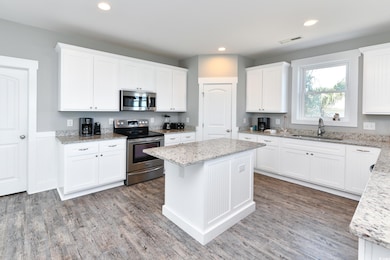 Kitchen featuring sink, light stone counters, appl