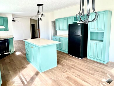 Kitchen with a textured ceiling, a kitchen island,