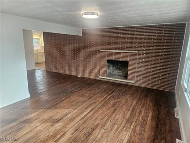 Unfurnished living room with dark wood finished floors, brick wall, a fireplace, and a textured ceiling