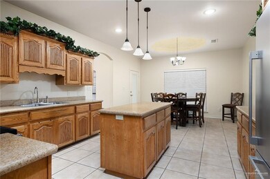 Kitchen with a center island, sink, hanging light fixtures, light tile patterned floors, and a notable chandelier