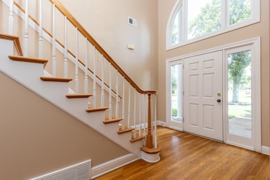 Entrance foyer with wood finished floors, healthy amount of natural light, a high ceiling, and stairs