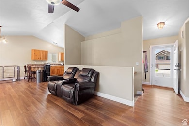 Living area with light wood-type flooring, lofted ceiling, and a ceiling fan