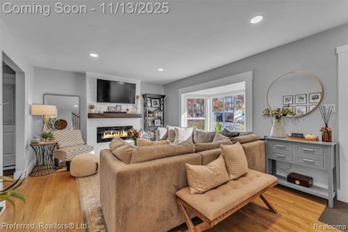 Living area with light oak wood flooring, recessed lighting, and a fireplace
