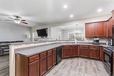 Kitchen with light wood-type flooring, open floor plan, a chandelier, healthy amount of natural light, and recessed lighting