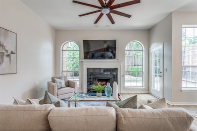 Living room with healthy amount of natural light, a tile fireplace, ceiling fan, and wood finished floors