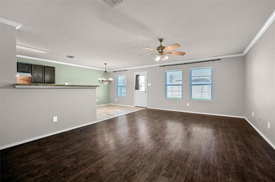 Unfurnished living room with ceiling fan with notable chandelier, hardwood / wood-style flooring, and ornamental molding