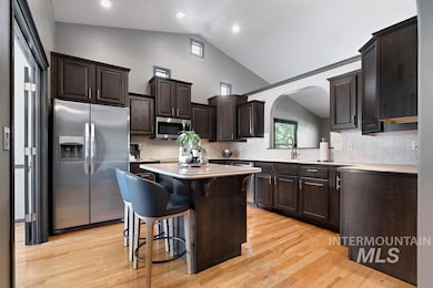 Kitchen with backsplash, a breakfast bar, stainless steel appliances, dark brown cabinets, and a kitchen island