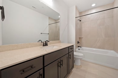 Bathroom featuring vanity, light tile patterned floors, bathing tub / shower combination, and recessed lighting