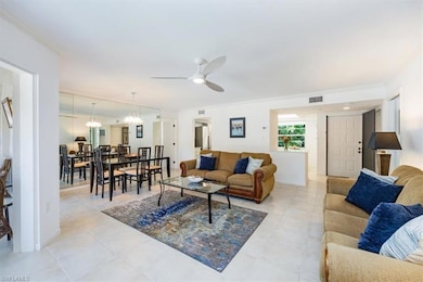 Living room featuring light tile patterned floors, visible vents, ceiling fan with notable chandelier, and ornamental molding