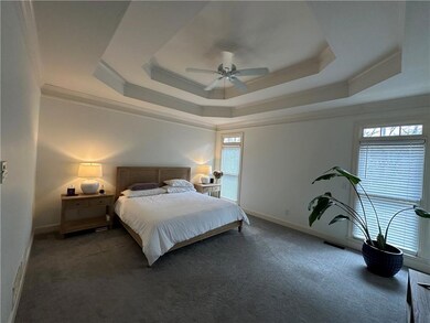 Carpeted bedroom featuring multiple windows, a tra