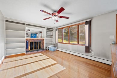 Living room with fireplace, ceiling fan, bookshelves and hardwood floors