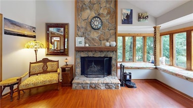 Living room with wood finished floors, a fireplace, and high vaulted ceiling