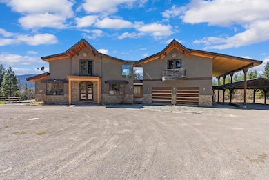 View of front of home featuring french doors, an attached garage, stone siding, and stucco siding