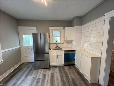 Kitchen featuring backsplash, light countertops, hardwood flooring, white cabinetry, plenty of natural light, and stainless steel appliances