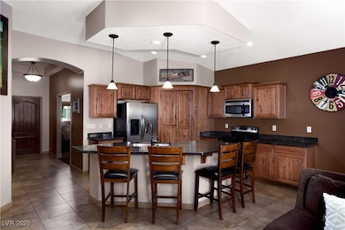 Kitchen with arched walkways, brown cabinetry, sta