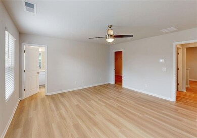 Empty room featuring light wood-style flooring, a ceiling fan, and baseboards