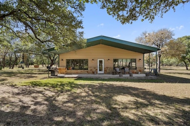 Back of house featuring stone siding, a yard, and