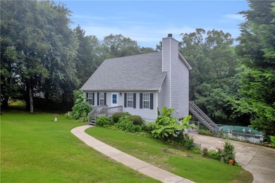 View of front facade featuring a front lawn, concrete driveway, a chimney, and roof with shingles